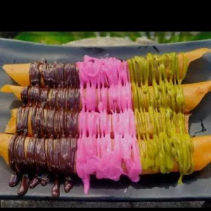 Banana ROLL1porsi isi 8pcs. .Gulungan pisang renyah dengan saus cokelat dan warna-warni.